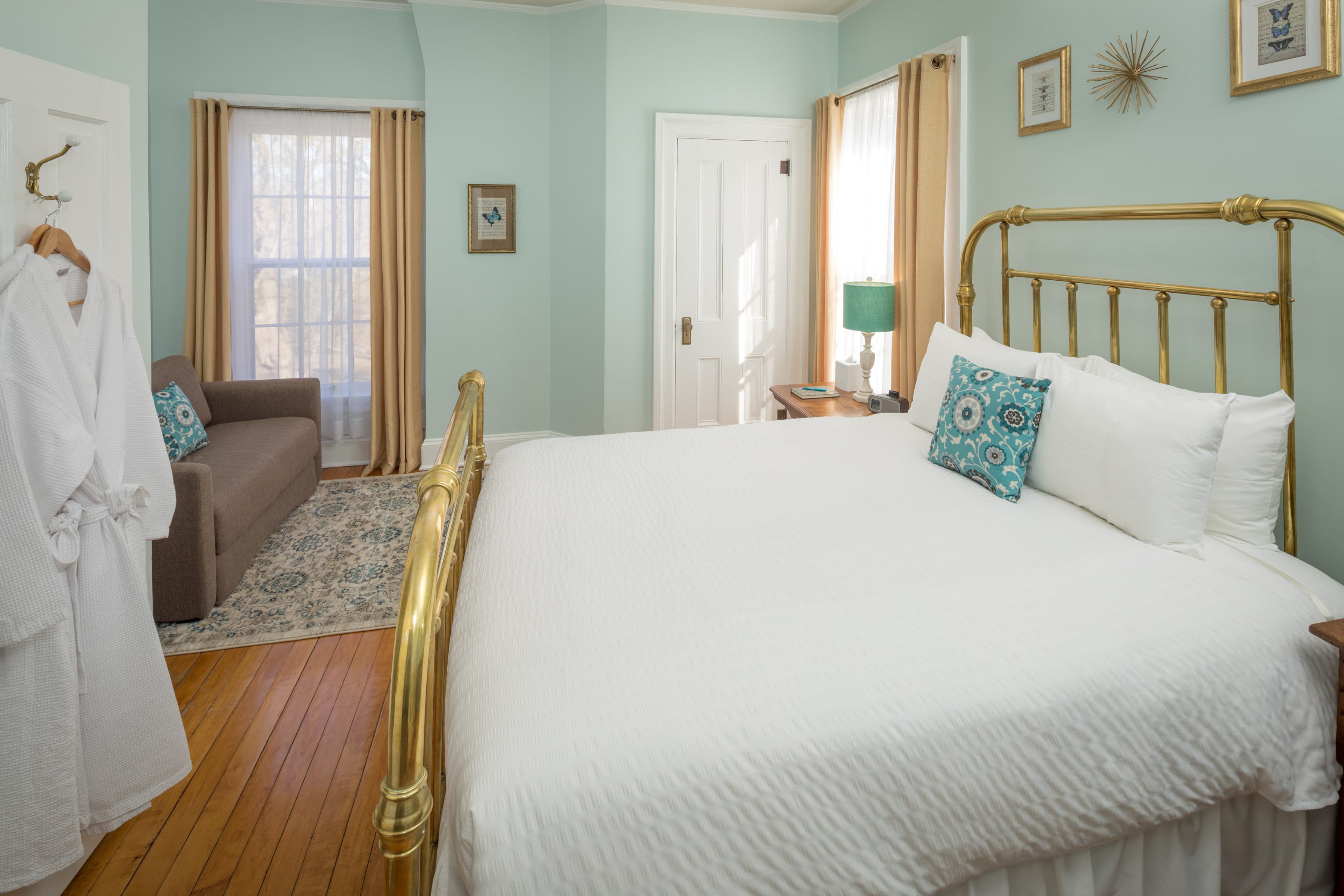 A spacious bedroom with forest green (recently changed) walls and a luxurious queen brass bed with antique bronze finish. A medium brown sofa bed is visible in the background.