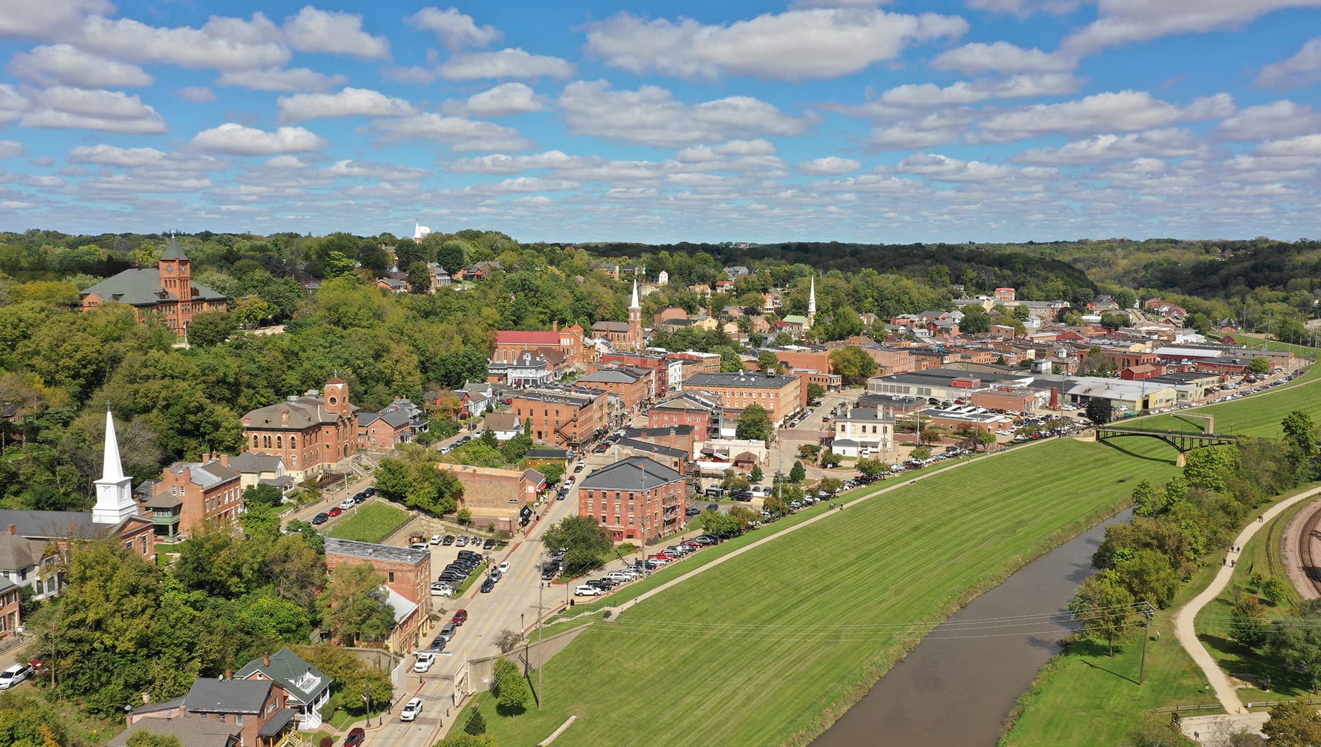 Aerial view of a small town featuring historic buildings, greenery, and a winding river.