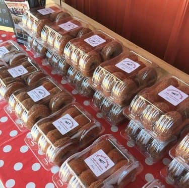 A display of packaged baked goods in clear containers on a polka dot tablecloth.