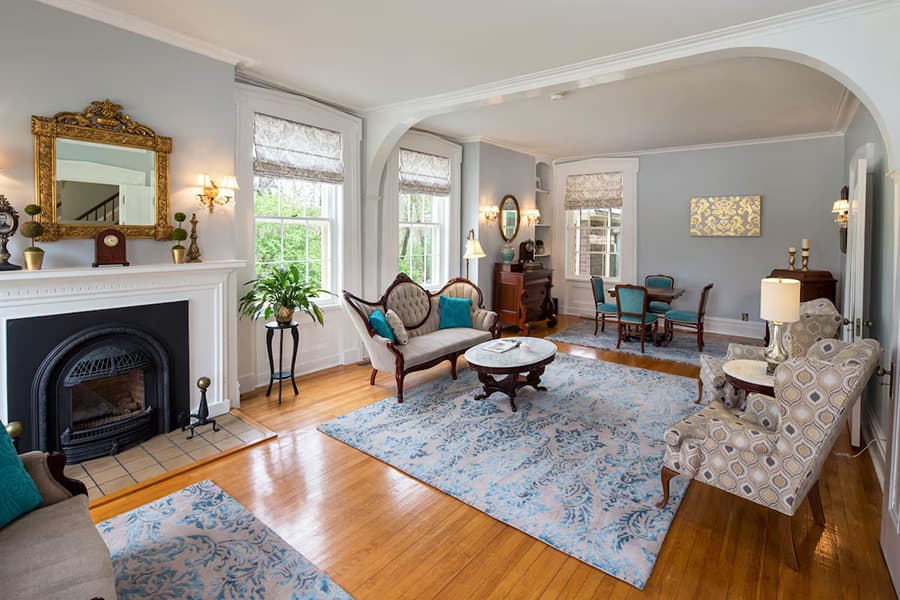 A spacious living room featuring elegant furniture, a patterned rug, and large windows with natural light.