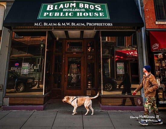 A person walks their dog in front of the Blaum Bros. Distilling Co. Public House.