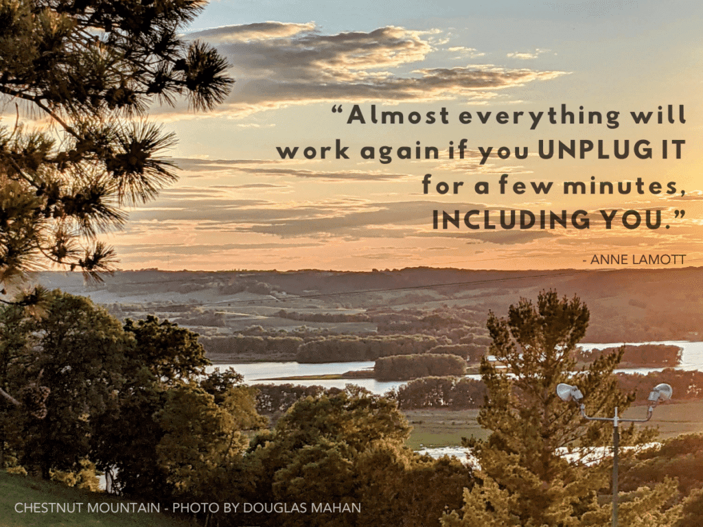 A scenic sunset view over rolling hills with a quote by Anne Lamott about unplugging for a moment.