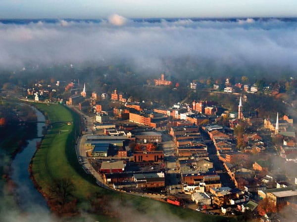 A town of 1800s buildings from above with a river flowing next to it