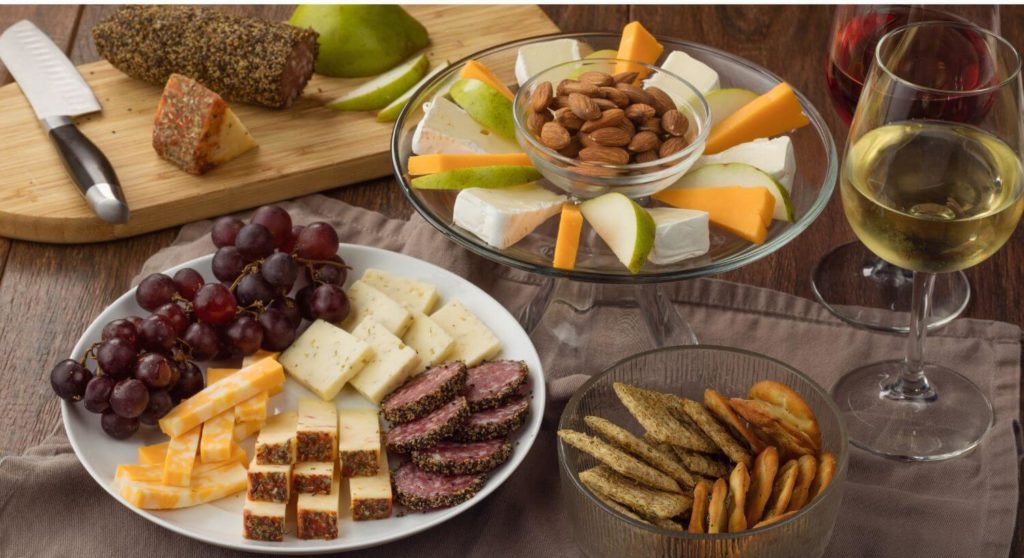 A variety of fruits, cheeses, and nuts with a glasses of red and white wine.