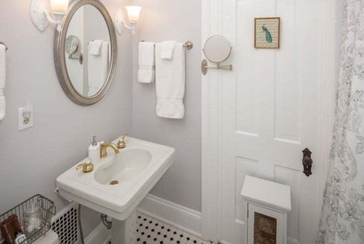 bathroom with white pedestal sink, oval mirror, white door and white towels