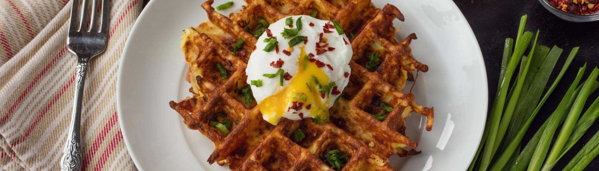 Waffles with poached eggs on a white plate with greens